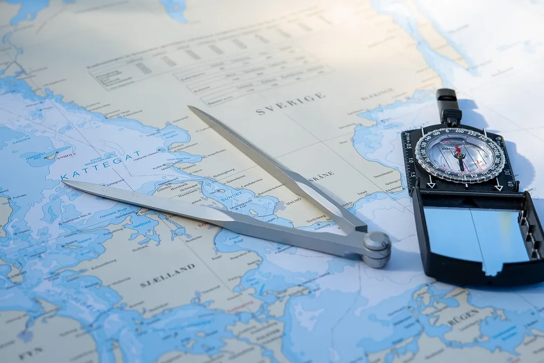 Carte marine, compas et boussole posés sur une table